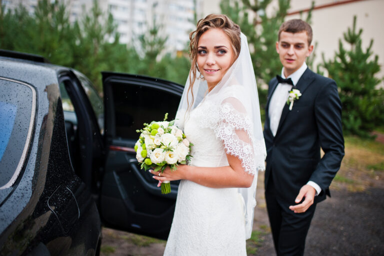 Groom and bride near wedding car