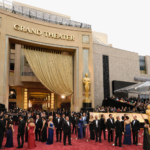 Red carpet gala event outside a grand theater with formally dressed guests arriving with executive transportation service.