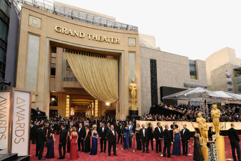 Red carpet gala event outside a grand theater with formally dressed guests arriving with executive transportation service.