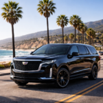 Black Cadillac Escalade driving along the Malibu coastline with ocean view and palm trees